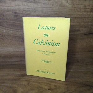May include: A hardcover book with a yellow dust jacket featuring green text that reads Lectures on Calvinism, The Stone Foundation Lectures, and by Abraham Kuyper, with a small decorative flourish centered above the author's name.