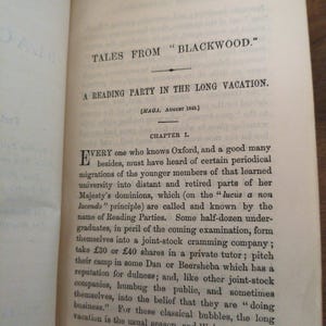 May include: An open book page featuring the title TALES FROM BLACKWOOD and the chapter heading A READING PARTY IN THE LONG VACATION. The text begins with the letter E and discusses university students forming a joint-stock cramming company.