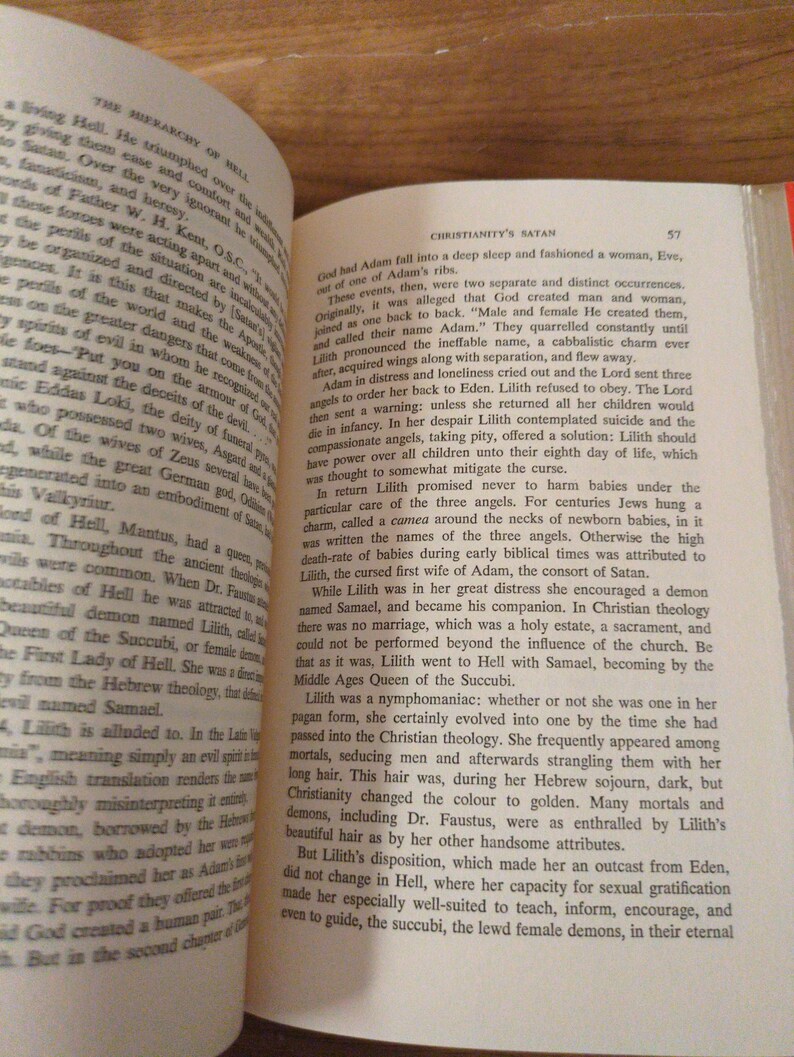 May include: An open book with text discussing Christianity's Satan and the hierarchy of Hell. The pages are aged, with black text. The book rests on a wooden surface.