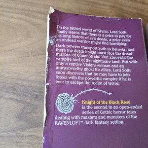Puede incluir: Primer plano de una portada de libro con fondo morado. El texto dice "Knight of the Black Rose" y describe un cuento de terror g&oacute;tico. Tambi&eacute;n es visible una ilustraci&oacute;n de una rosa blanca. El libro es parte de la serie Ravenloft.