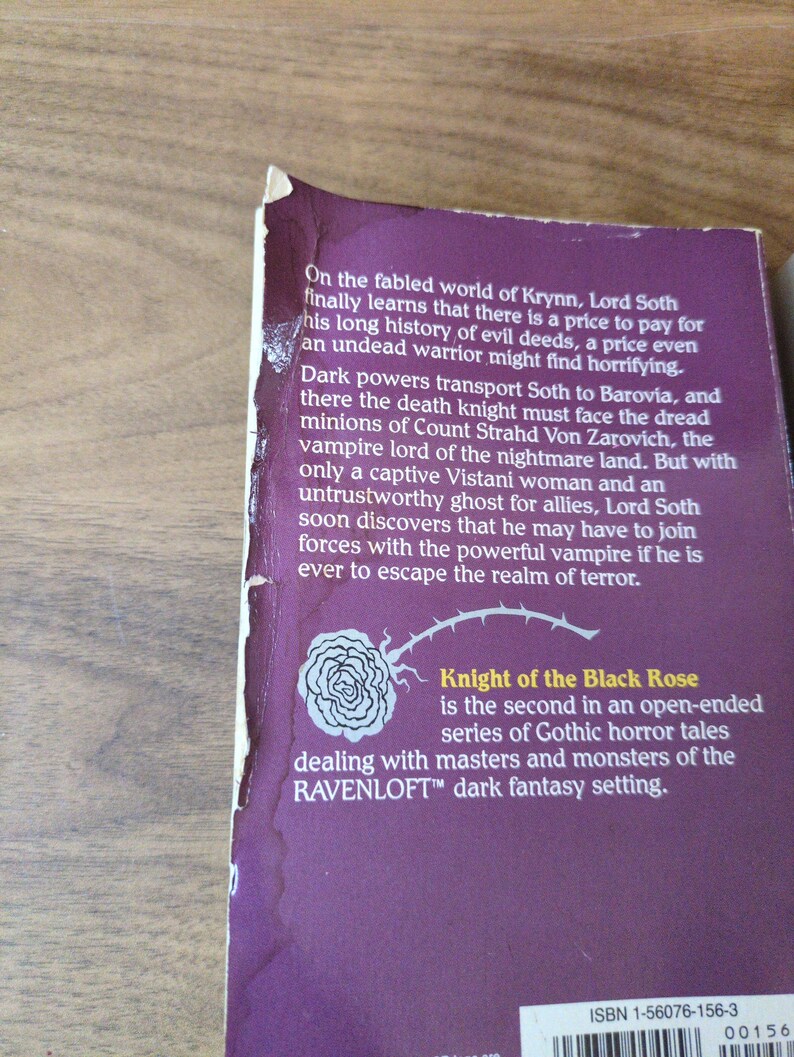 Puede incluir: Primer plano de una portada de libro con fondo morado. El texto dice "Knight of the Black Rose" y describe un cuento de terror g&oacute;tico. Tambi&eacute;n es visible una ilustraci&oacute;n de una rosa blanca. El libro es parte de la serie Ravenloft.