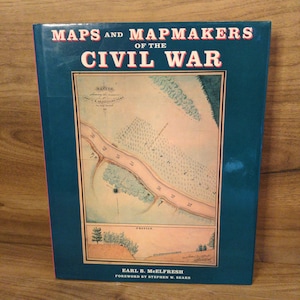 May include: A hardcover book titled "Maps and Mapmakers of the Civil War." The cover is dark blue with red and white text. The book features a detailed map illustration in the center, with the author's name and foreword details at the bottom.