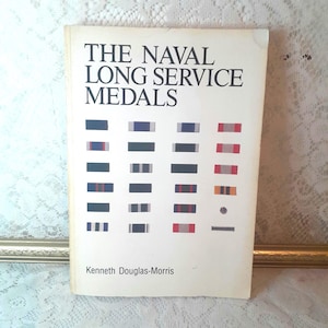 May include: A white book with the title "The Naval Long Service Medals" in black text. The book features a chart of different medals with various colored ribbons.