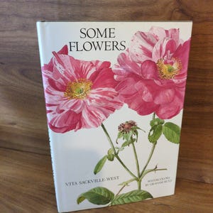 May include: A hardcover book titled "SOME FLOWERS" with a watercolor illustration of pink and white flowers. The book's cover features the author's name, Vita Sackville-West, and the artist's name, Graham Rust.