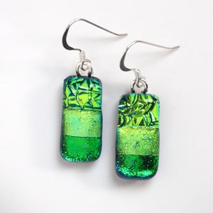 May include: A pair of green glass dangle earrings with silver hooks. The glass is layered and has a textured, iridescent finish.