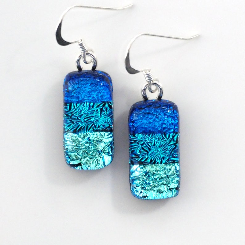 Blue, teal, and ice blue fused dichroic glass earrings, stripes of sparkly blue glass, hanging from sterling silver ear wires.