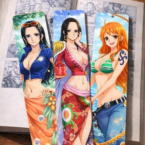 Puede incluir: Tres marcapáginas de estilo anime con personajes femeninos. Los marcapáginas representan a mujeres con varios atuendos, incluyendo una chaqueta azul y falda naranja, un vestido rojo y un bikini verde con vaqueros azules. Los marcapáginas están colocados frente a un libro abierto.