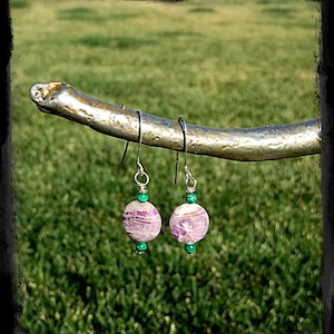 May include: A pair of silver earrings with purple and white striped round beads and green beads.