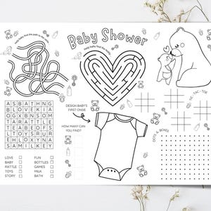 May include: Black and white baby shower activity sheet featuring a maze, word search, tic-tac-toe, and other games. Includes a heart-shaped maze, a onesie design area, and illustrations of bears, bottles, and rattles.