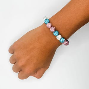 May include: A bracelet with white, pink, and blue sparkly beads.