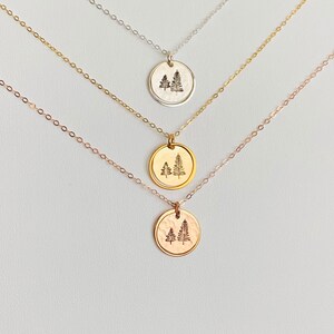 May include: Three gold necklaces with a tree pendant. The necklaces are layered on top of each other, with the top necklace being silver, the middle necklace being gold, and the bottom necklace being rose gold.