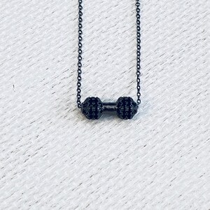 Peut inclure: Un collier &agrave; cha&icirc;ne noire avec un petit pendentif halt&egrave;re noir. L'halt&egrave;re est recouvert de petites pierres noires.
