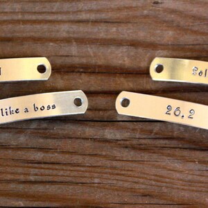 May include: Four silver metal tags with different engraved messages. The tags read "RUN", "like a boss", "Sole Sisters", and "26.2".