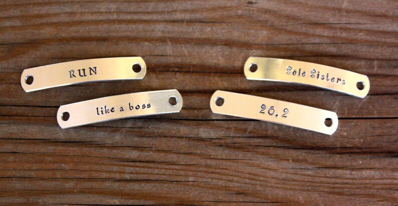 May include: Four silver metal tags with different engraved messages. The tags read "RUN", "like a boss", "Sole Sisters", and "26.2".
