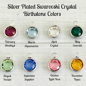 May include: Twelve silver-plated charms with Swarovski crystals in different colors, representing the birthstones for each month of the year. The charms are arranged in two rows of six, with the month and birthstone name listed below each charm.