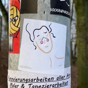 Könnte beinhalten: Ein weißer Aufkleber mit einer Strichzeichnung eines Gesichts mit zwei roten Kirschen auf der Nase. Der Aufkleber hat den Text "ARIMSOL" unten links.