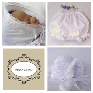 May include: White baby bonnet with lace trim and a white smocked baby bonnet with a white satin ribbon. The text "ADD A LINING" is in a decorative frame.