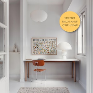 May include: A bright, minimalist interior with a white desk, orange chair, and a framed map labeled "ROUTE ZUR 60". A white mushroom-shaped lamp sits on the desk. A round, white pendant light hangs from the ceiling.