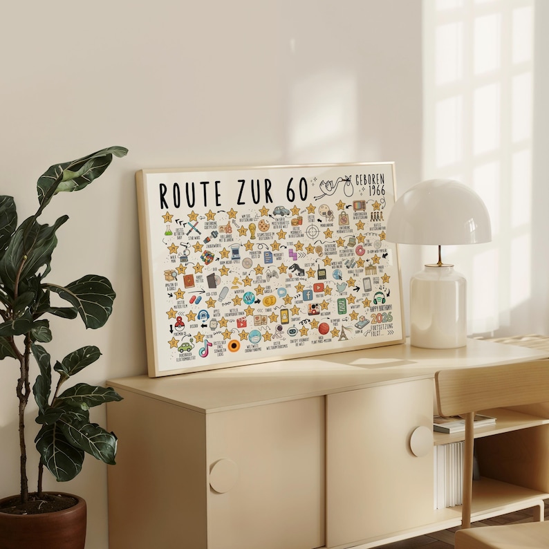 May include: A framed print with the text "ROUTE ZUR 60" and "GEBOREN 1966" in black. The print features numerous hand-drawn icons and stars, with a cream-colored background. The frame is a light wood color.
