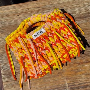 K&ouml;nnte beinhalten: Handgewebte Handtasche in Gelb-, Orange- und Rosat&ouml;nen. Die Tasche hat einen Griff und Fransen. Auf dem Etikett der Tasche steht "barwy".