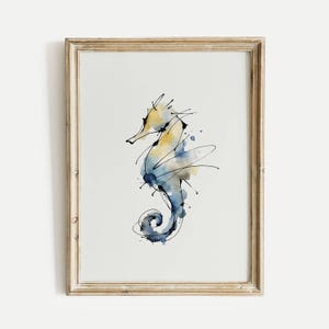Puede incluir: Impresión artística de un caballito de mar en acuarela en un marco dorado. El caballito de mar está representado con lavados de acuarela amarillos y azules y detalles en tinta negra. La obra de arte está enmarcada en un marco de madera dorada.