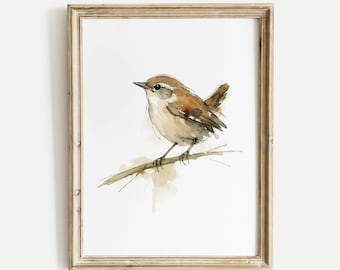 May include: Watercolor painting of a small brown bird perched on a branch, set against a white background. The bird has a light-colored chest and a dark beak. The artwork is framed in a light brown wooden frame, adding a rustic touch to the piece.