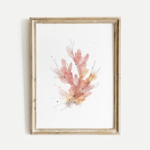 Puede incluir: Lámina artística enmarcada con un diseño de coral en acuarela en tonos melocotón y naranja, acentuado con finas líneas negras. La obra de arte está sobre un fondo blanco y enmarcada en un marco de madera dorada, creando una estética minimalista.