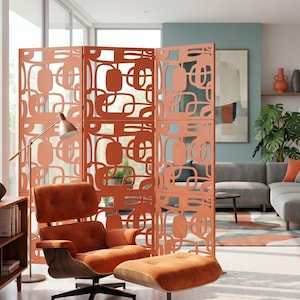 Op de afbeelding: Een woonkamer in mid-century modern stijl met een koraalkleurige kamerscherm met een geometrisch patroon. Een oranje fauteuil en ottoman staan voor de scheidingswand. Een vloerlamp en een grijze bank maken de scène compleet.