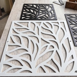 Op de afbeelding: Een vierkant metalen paneel met een lasergesneden bladpatroon met ingewikkelde, vloeiende rankachtige uitsparingen. Het paneel is afgewerkt in een matte witte kleur en bevat kleine ronde montagegaten aan de linker- en rechterzijkanten.