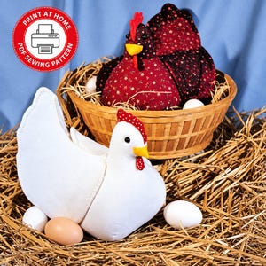 Puede incluir: Dos gallinas de tela, una blanca y otra roja oscura con patrones florales, con picos amarillos y crestas rojas. La gallina blanca está sobre paja con huevos, la roja en una cesta de madera. Texto: PRINT AT HOME PDF SEWING PATTERN.
