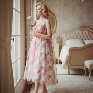 May include: A woman in a floral print dress with a pink ribbon sash stands by a window, holding a pink rose. The dress features a white background with pink rose patterns. The image includes a bedroom setting with a bed and a "Print at Home PDF Sewing Pattern" logo.