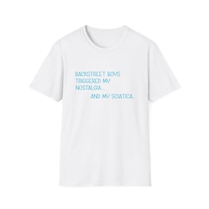 Puede incluir: Una camiseta blanca de cuello redondo con el texto en azul claro: "BACKSTREET BOYS TRIGGERED MY NOSTALGIA... AND MY SCIATICA." La camiseta está hecha de un material suave, adecuada para uso casual.