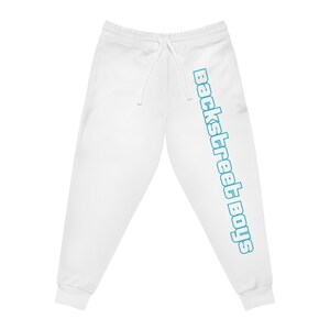 Può includere: Pantaloni della tuta bianchi con vita con coulisse e la scritta "Backstreet Boys" stampata verticalmente in verde acqua sulla gamba sinistra. I pantaloni della tuta hanno una vestibilità ampia.