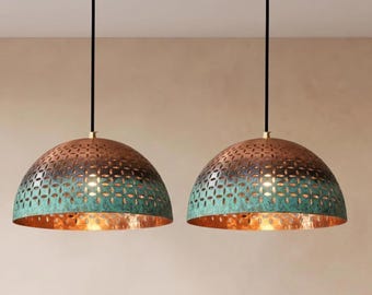 May include: Two dome-shaped pendant lights featuring a metallic copper finish with a teal green patina. The shades have a repeating laser-cut floral pattern, black suspension cords, and circular brass-toned ceiling mounts.