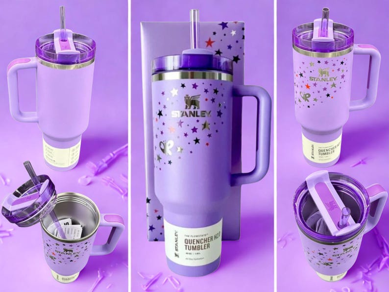 Op de afbeelding: Een verzameling lavendelkleurige Stanley Quencher H2.0 FlowState-bekers met handvatten, deksels en rietjes. De bekers zijn versierd met gouden sterren en het Stanley-logo. De tekst "QUENCHER H2.0 TUMBLER" is zichtbaar op het label.