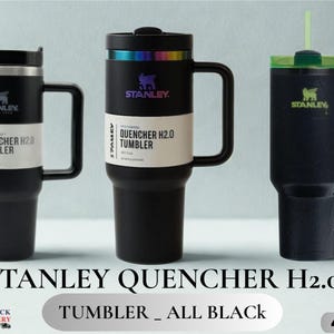 May include: Three black Stanley Quencher H2.0 tumblers with handles and straws. The left and center tumblers feature white product labels reading Quencher H2.0 Tumbler. The center tumbler has an iridescent rim. The right tumbler has a green lid.