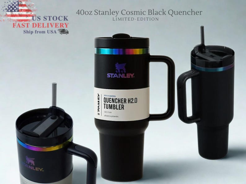 May include: Three black Stanley Cosmic Black Quencher tumblers with handles and straws. The tumblers have a rainbow iridescent band near the top and the text "STANLEY" is visible. The largest tumbler is labeled "40oz" and "QUENCHER H2.0 TUMBLER".