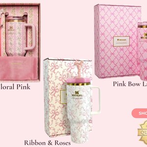 May include: Three Stanley tumblers with handles and lids, presented in decorative boxes. One features a pink floral pattern, another a pink bow lattice design, and the third a white ribbon and rose print. Each set includes a matching straw and accessory.