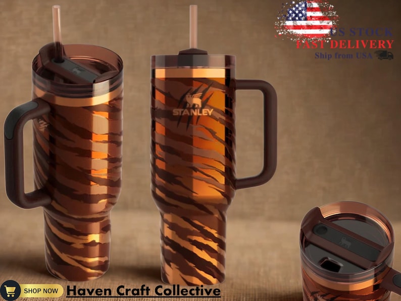 May include: Two Stanley brand travel mugs with a tiger stripe pattern in shades of brown and orange. Each mug has a handle, a lid, and a straw. The mugs are displayed on a brown background. The text "Haven Craft Collective" is at the bottom.