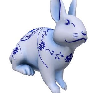 May include: A blue and white ceramic rabbit figurine with a delicate floral design. The rabbit is sitting on its hind legs with its front paws resting on its belly.