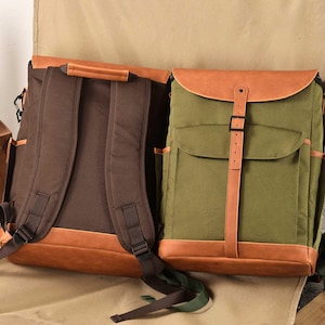 Puede incluir: Dos mochilas de lona con detalles de cuero. La mochila de la izquierda es marr&oacute;n con correas de cuero marr&oacute;n y una solapa de cuero marr&oacute;n. La mochila de la derecha es verde con correas de cuero marr&oacute;n y una solapa de cuero marr&oacute;n.