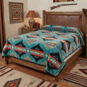 May include: A turquoise Southwestern-style blanket with a geometric pattern in black, orange, and tan covers a wooden bed frame. The blanket has a black border and is displayed in a bedroom setting with a matching rug.