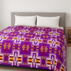 May include: A vibrant purple blanket with a geometric pattern in white, yellow, and red. The design features repeating cross-like shapes and triangular motifs. The blanket is on a bed with white pillows.