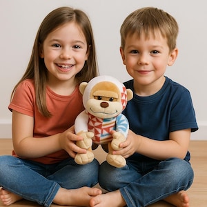 May include: A plush monkey toy with a white face, tan ears, and a patterned body in red, blue, and white. The monkey is held by two children, a girl and a boy, both smiling at the camera. The background is a plain white wall.