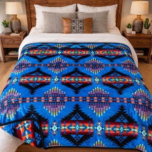 May include: A blue blanket with a geometric pattern in black, red, orange, and yellow. The blanket is on a bed with a wooden headboard and nightstands. The blanket's design features diamond and triangle shapes.