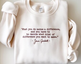 May include: Cream-colored sweatshirt with the quote "What you do makes a difference, and you have to decide what kind of difference you want to make." by Jane Goodall, in a dark brown script. The sweatshirt has long sleeves.