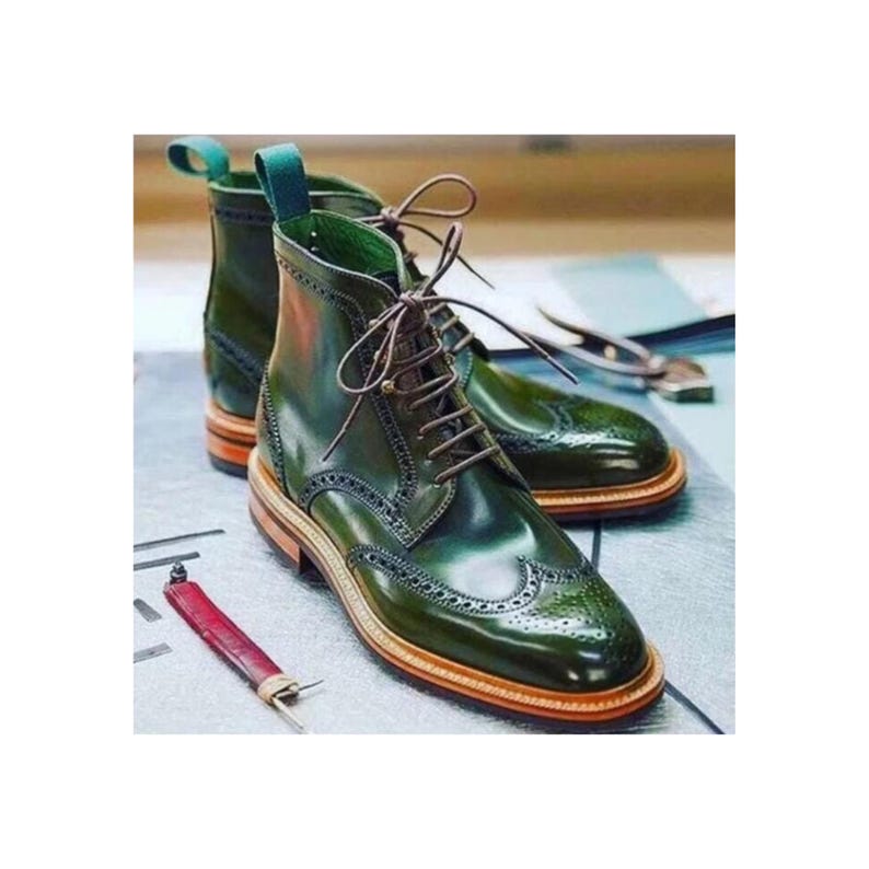 May include: A pair of green leather lace-up boots with brogue detailing. The boots have a brown leather sole and a green leather heel.