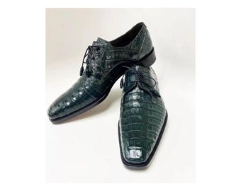 May include: A pair of dark green crocodile leather dress shoes with lace-up closures.