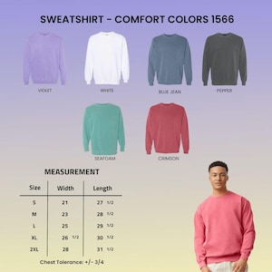 May include: A selection of Comfort Colors 1566 sweatshirts in violet, white, blue jean, pepper, seafoam, and crimson. A measurement chart shows sizes S to 2XL with width and length in inches. A person is wearing a crimson sweatshirt.