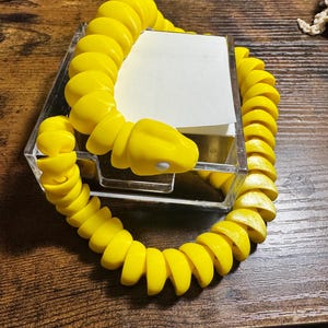 May include: A set of three ceramic mugs with a speckled, matte finish. The mugs are in shades of cream, light gray, and dark gray. Each mug has a simple, minimalist design and a rounded handle. The mugs are likely for coffee or tea.